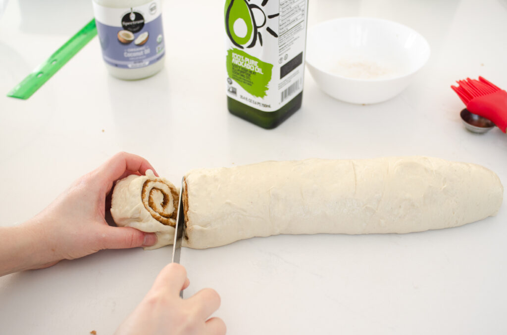 Slicing the dairy free cinnamon rolls with a serrated knife. 