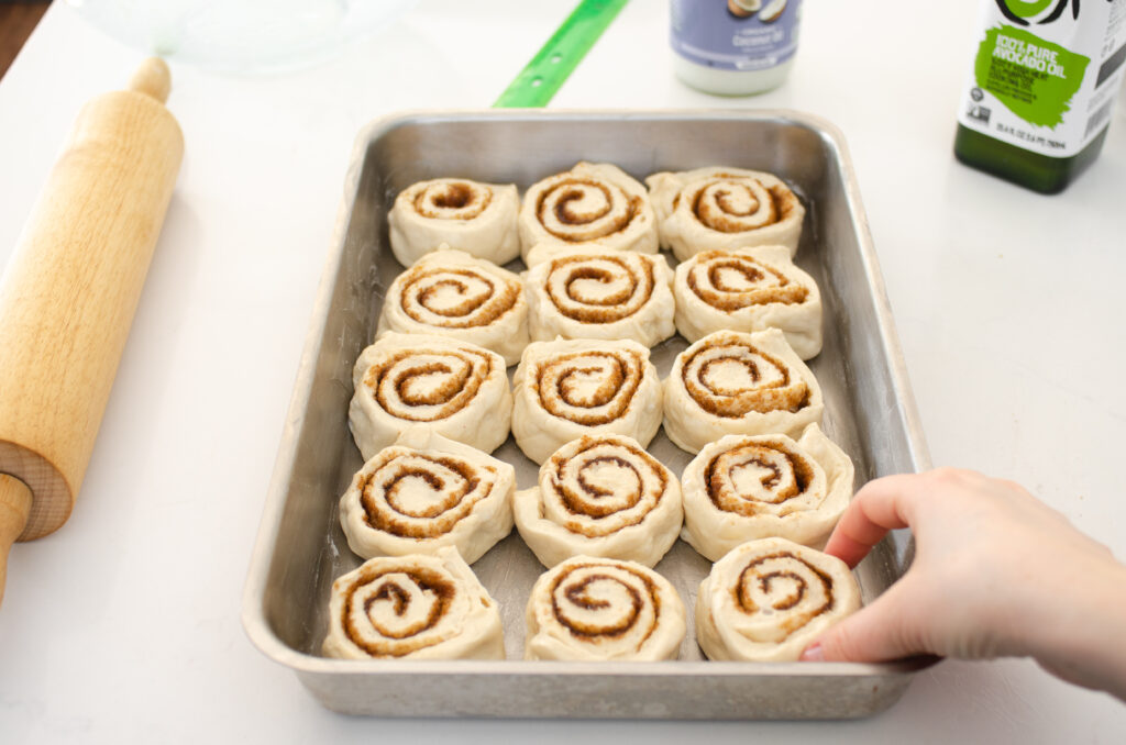 Placing the sliced cinnamon buns into the prepared pan.