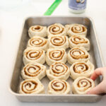 Placing the sliced cinnamon buns into the prepared pan.