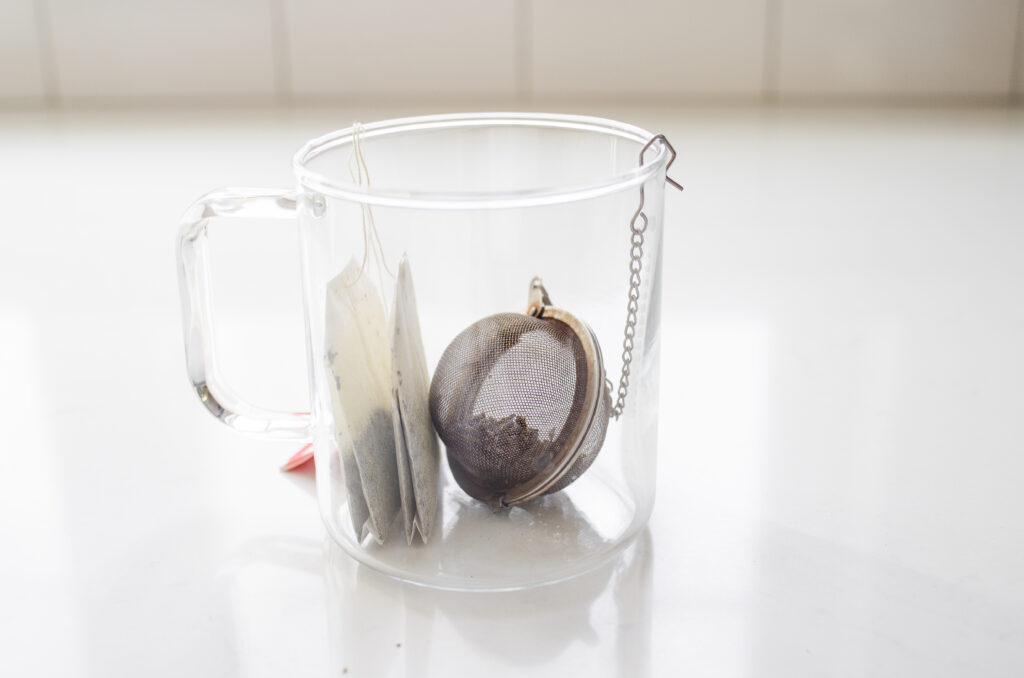 Placing the tea bags and strainer in a mug to make the London Fog latte.