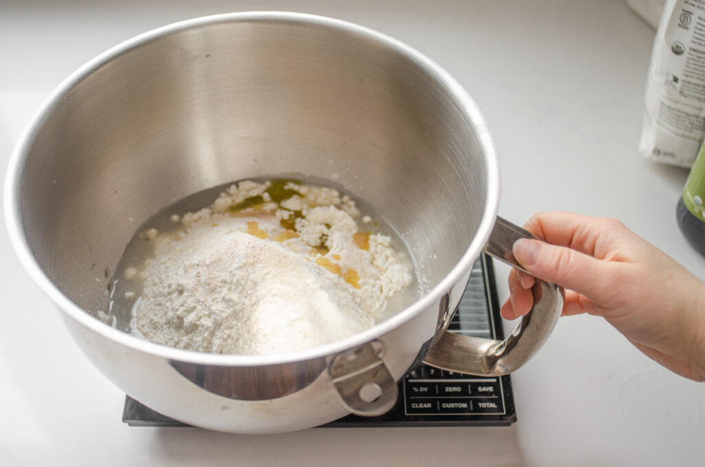 Placing all of the dough ingredients in the bowl of a stand mixer.
