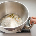 Placing all of the dough ingredients in the bowl of a stand mixer.