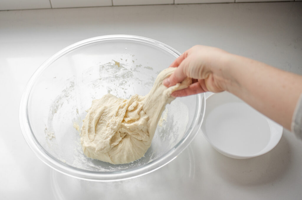 Performing the first stretch and fold sequence to develop the gluten in the sourdough pizza crust. 