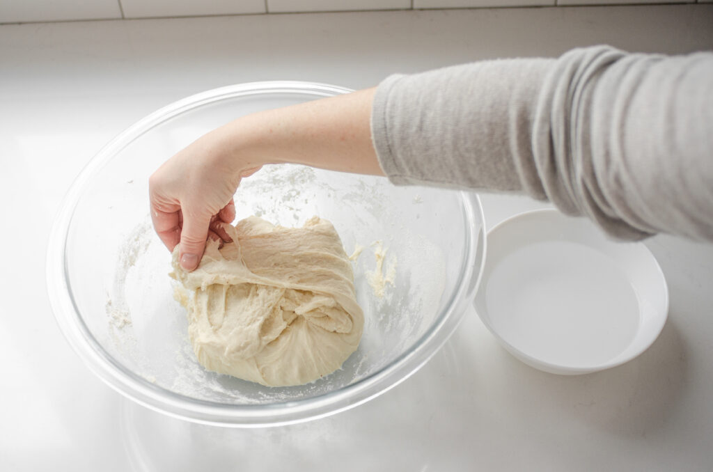 Performing the first stretch and fold sequence to develop the gluten in the sourdough pizza crust. 