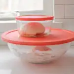 Placing the sourdough pizza dough in greased lidded containers.