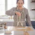 Dusting a piece of parchment paper with flour in preparation for shaping the sourdough pizza crust.