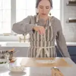 Dusting a piece of parchment paper with flour in preparation for shaping the sourdough pizza crust.