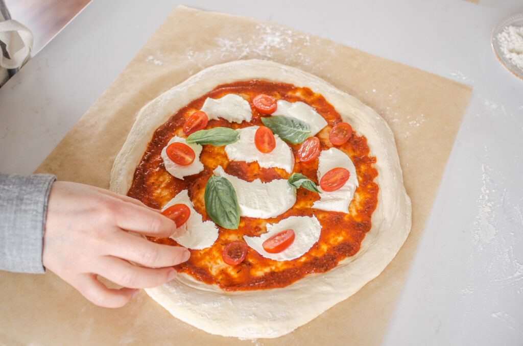 Making a Neapolitan pizza with fresh tomatoes, fresh mozzarella cheese, and basil. 