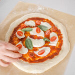 Making a Neapolitan pizza with fresh tomatoes, fresh mozzarella cheese, and basil.