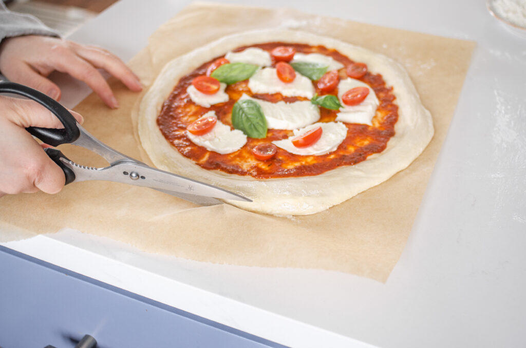 Trimming the parchment paper with scissors so it doesn't burn.