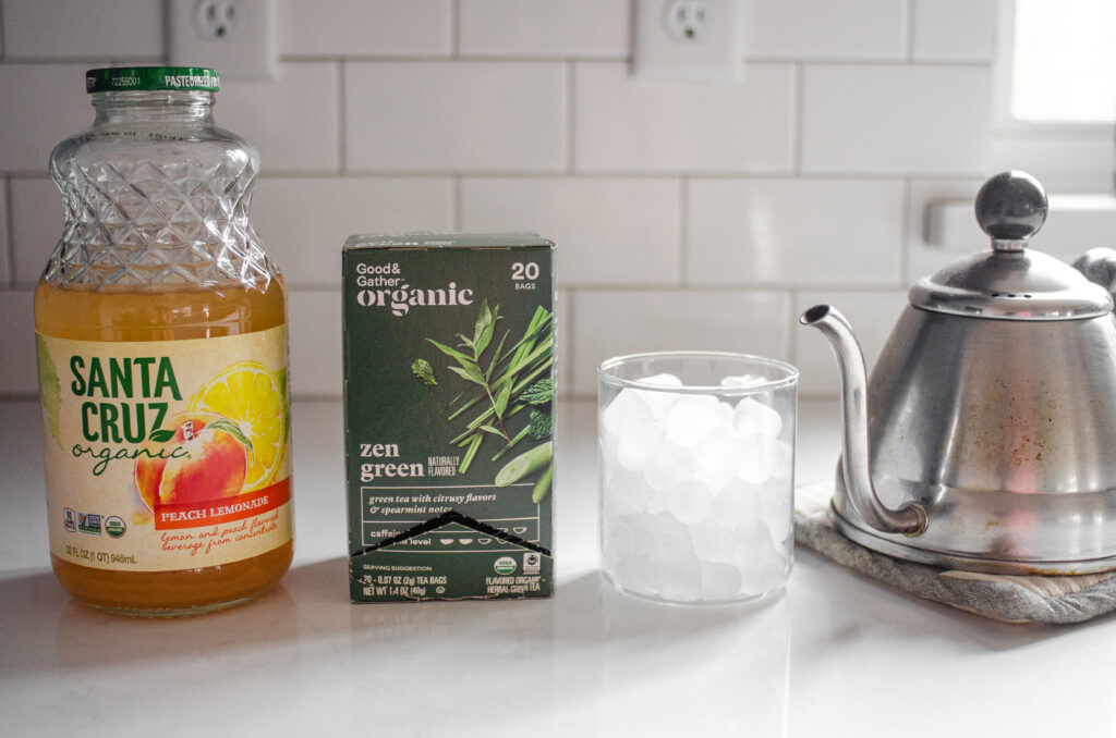 All of the ingredients needed to make a peach green tea lemonade (Starbucks Copycat) laid out on a white counter.