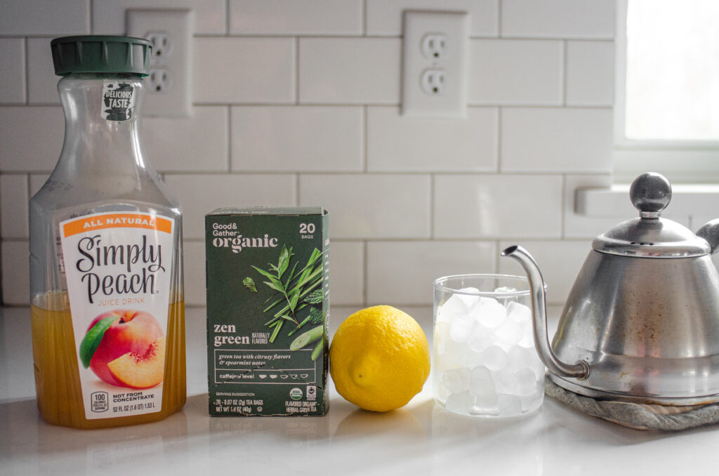 All of the ingredients needed to make a Starbucks Peach Green Tea Lemonade at home laid out on a white countertop.