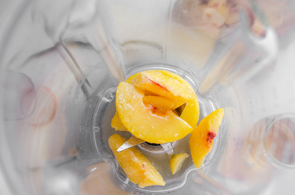 Frozen peaches in a blender with lemon juice and maple syrup.