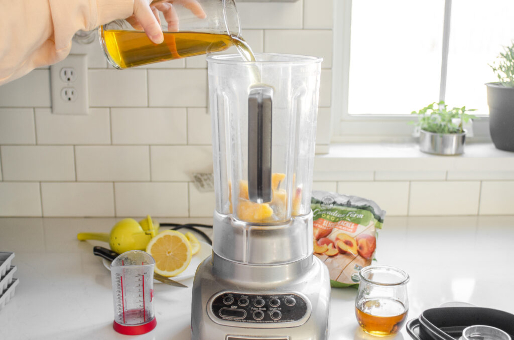 Pouring the green tea on top of the peaches in the blender.