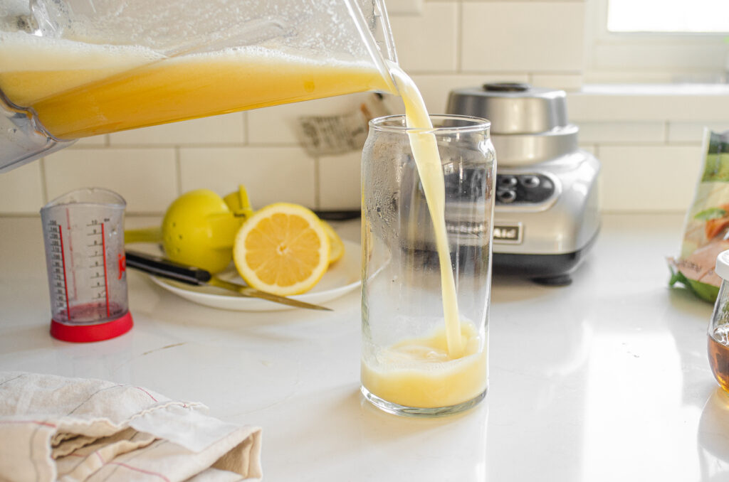 Pouring the homemade Starbucks peach green tea lemonade recipe into a tall glass.