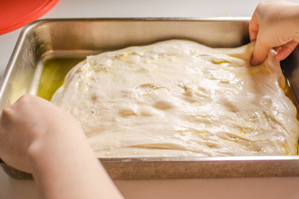 Stretching out the sourdough focaccia dough in the pan.