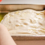 Stretching out the sourdough focaccia dough in the pan.