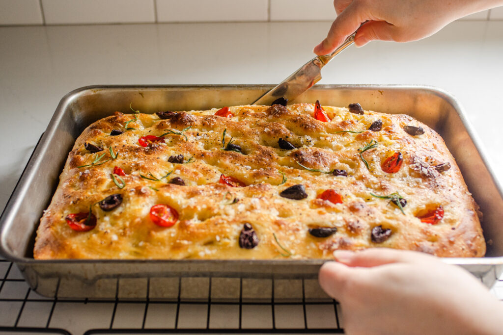 Running a knife around the edges of the cooked sourdough focaccia.