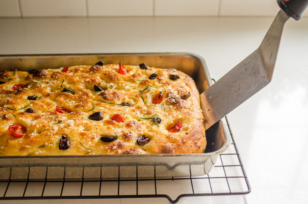 Using a metal spatula to remove the focaccia from the pan.