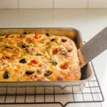 Using a metal spatula to remove the focaccia from the pan.