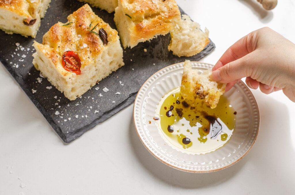 Dipping the sourdough focaccia into a little plate of extra virgin olive oil and balsamic vinegar.