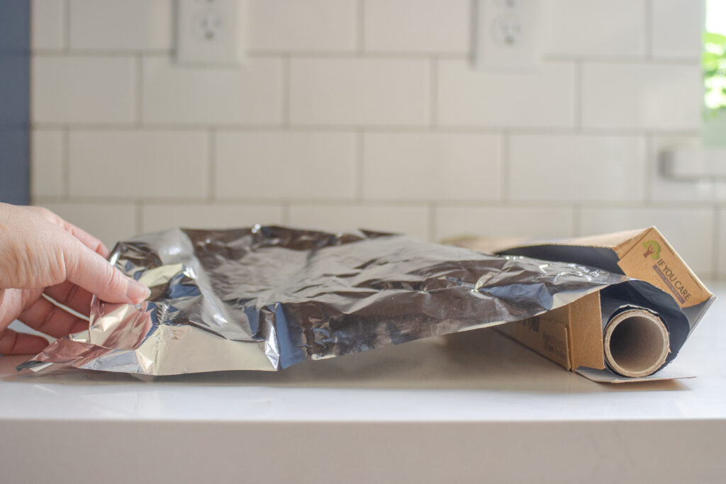 Pulling out a sheet of aluminum foil to use as a parchment paper substitute for baking.