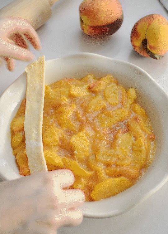 Arranging the pie crust strips in a lattice pattern on top of the peach filling.