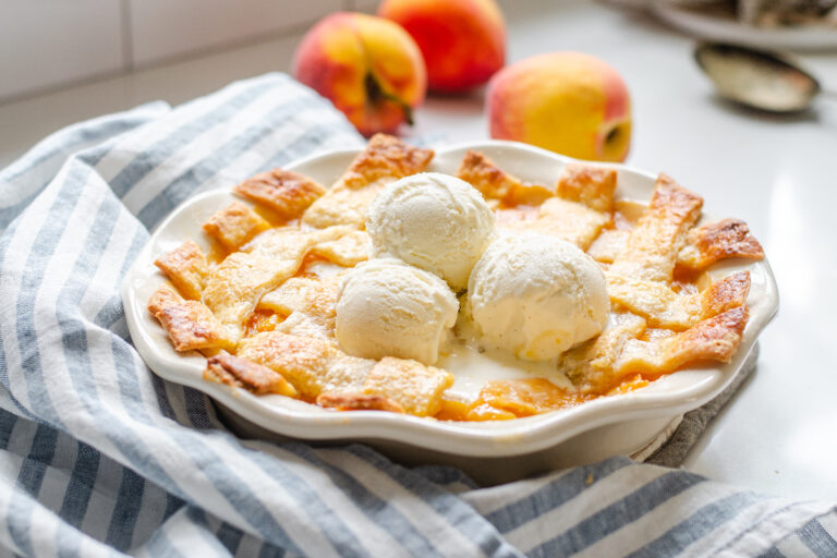 A southern peach cobbler baked in a pie dish with a lattice pie crust topping.