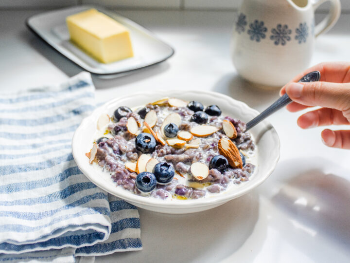 A bowl of blueberry oatmeal with fresh blueberries and sliced almonds on top.