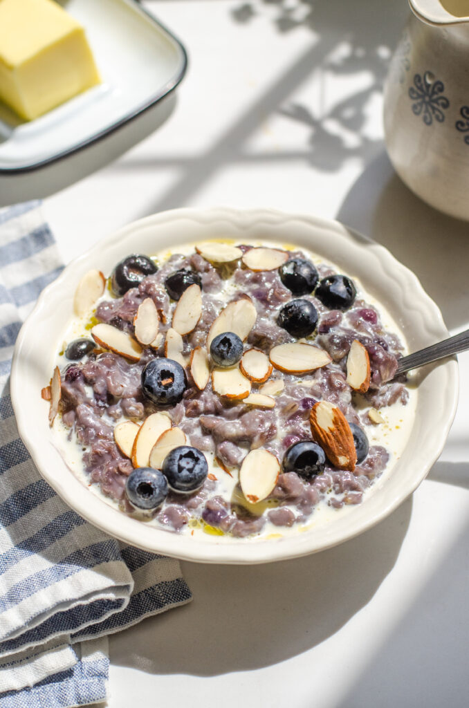 A bowl of blueberry oatmeal with fresh blueberries and sliced almonds on top.