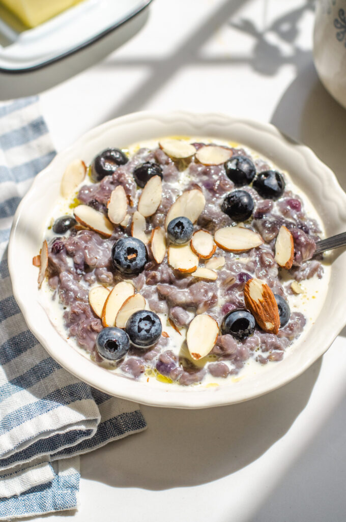 A bowl of blueberry oatmeal with fresh blueberries and sliced almonds on top.