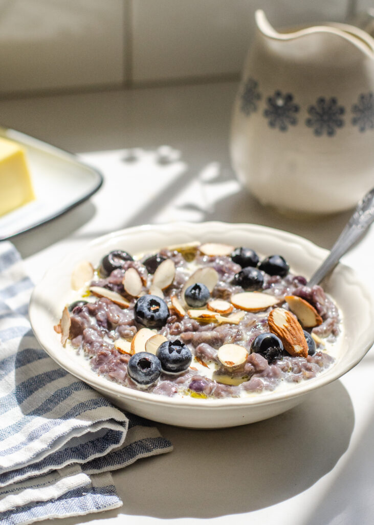 A bowl of blueberry oatmeal with fresh blueberries and sliced almonds on top.