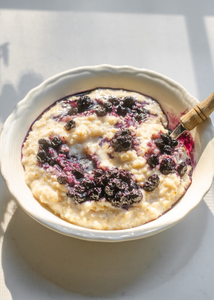 A bowl of oatmeal with blueberry compote swirled in.