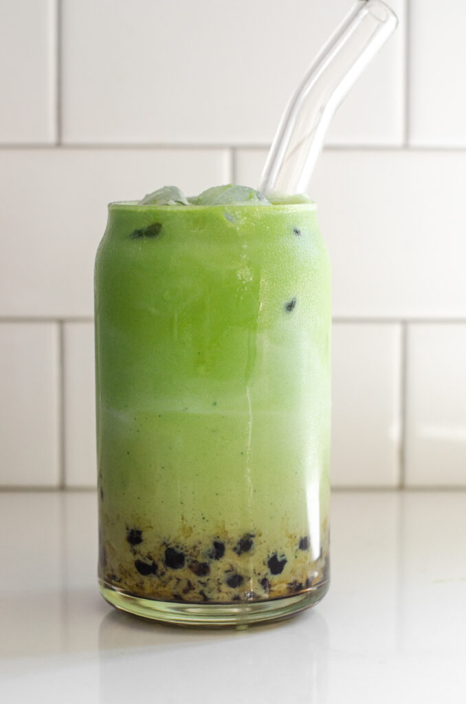 A glass of matcha milk tea with tapioca pearls (Boba).