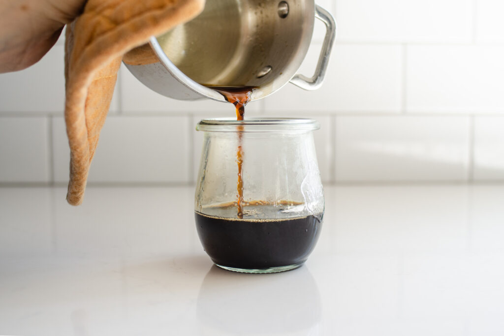 Pouring the finished brown sugar simple syrup into an airtight container. 