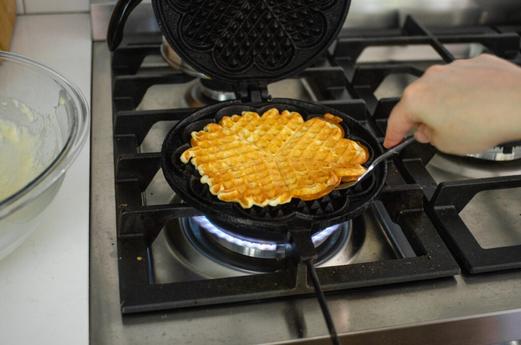 Cooking sourdough discard waffles in a cast iron waffle maker.