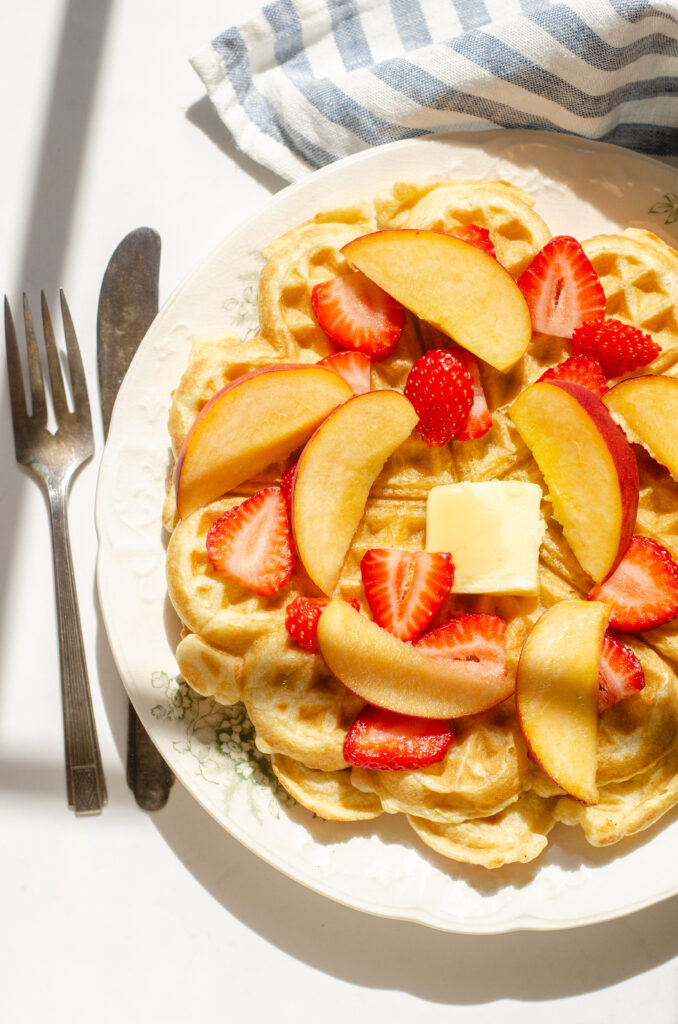 Sourdough discard waffles topped with peaches and strawberries.