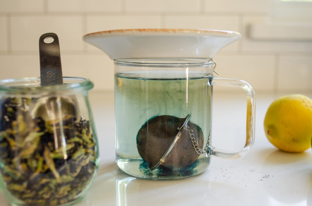 Brewing the hot butterfly pea tea in a mug with a plate on top.