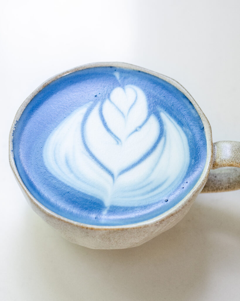 A mug of blue butterfly pea flower latte with latte art.