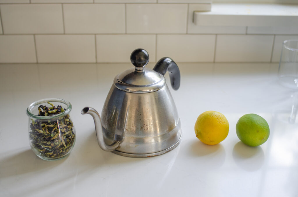 All of the ingredients needed to make hot butterfly pea tea laid out on a counter. 