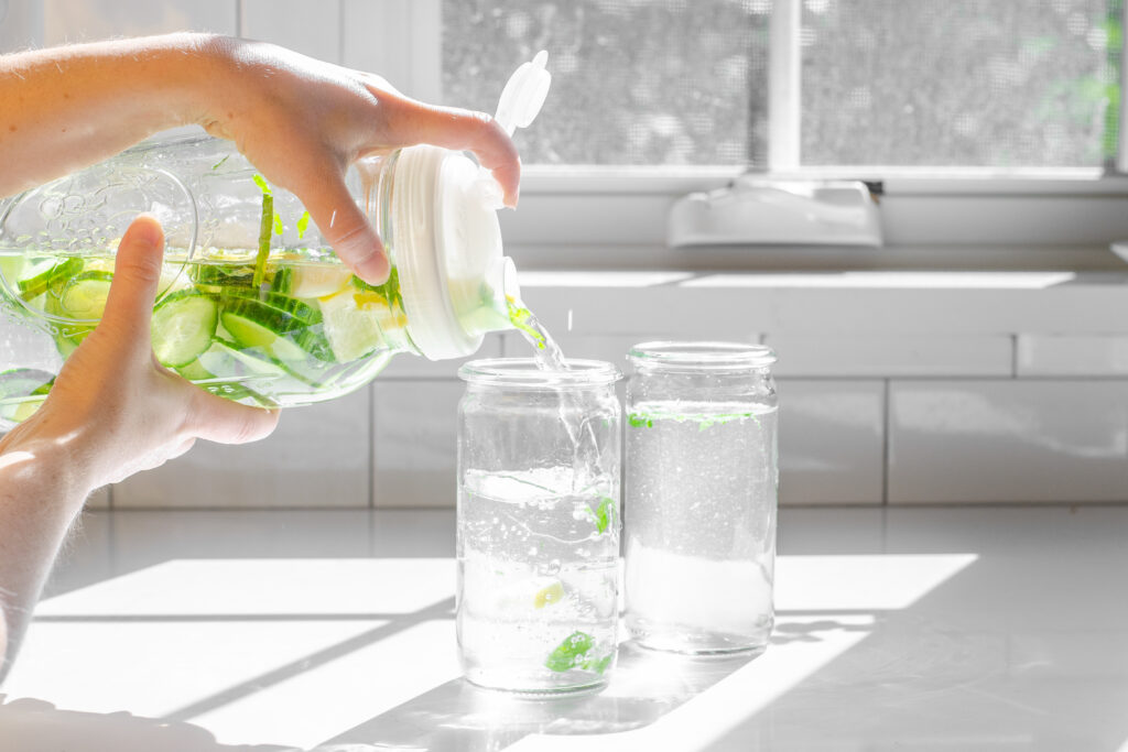 Pouring the infused water into drinking glasses.