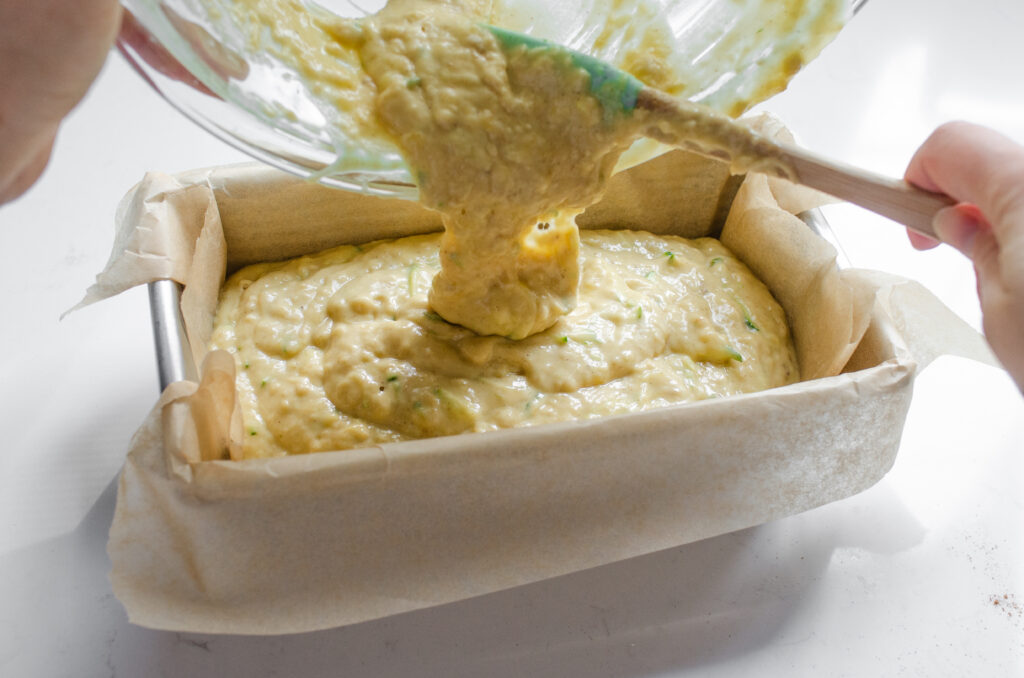 Scraping the batter into the prepared loaf pan.