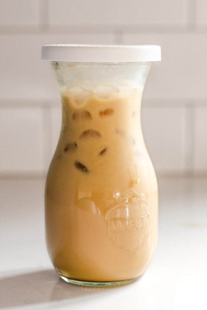 A jar of homemade Starbucks bottled Frappuccino on a white counter with white subway tile backsplash in the background. 