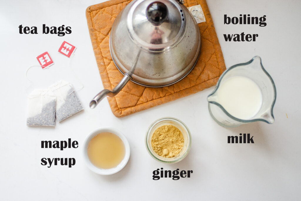 All the ingredients needed to make a Starbucks chai tea latte at home laid out on a white countertop.