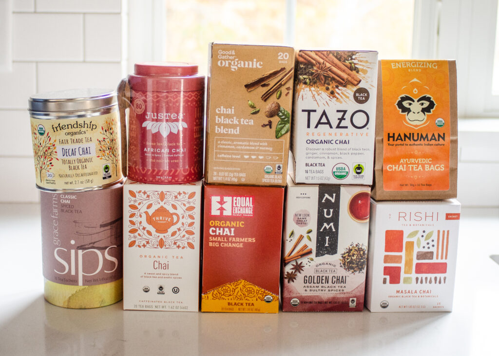 10 different organic chai tea brands stacked on top of each other on a white countertop.