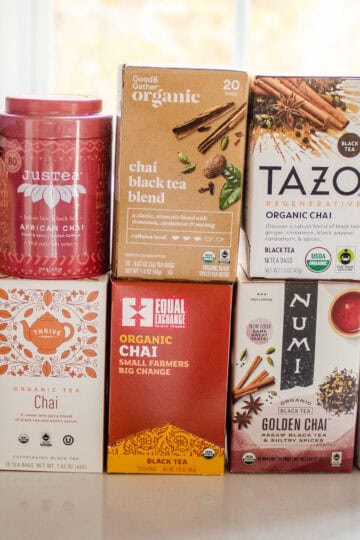10 different organic chai tea brands stacked on top of each other on a white countertop.