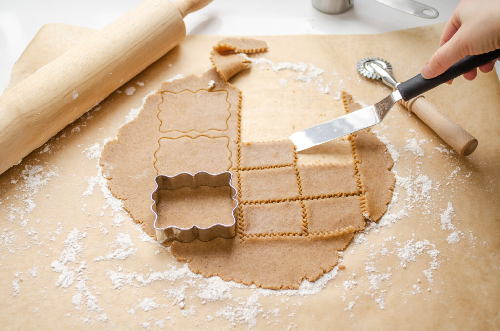 Using an offset spatula to move the cutout cookie to the prepared pan.