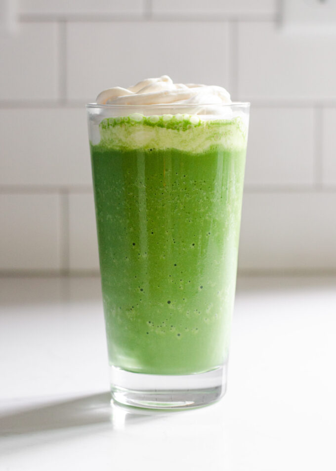 A glass of homemade Starbucks matcha Frappuccino on a white countertop.