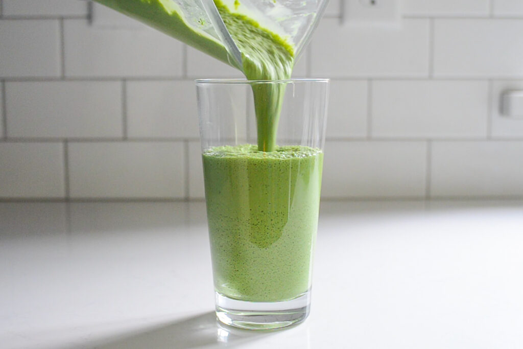 Pouring the matcha green tea Frappuccino into a 20 ounce clear glass.