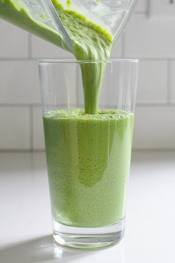 Pouring the matcha green tea Frappuccino into a 20 ounce clear glass.